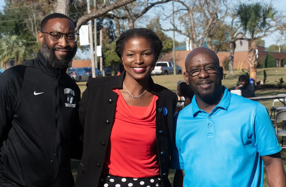 Three members of the Voorhees University community smiling together on campus